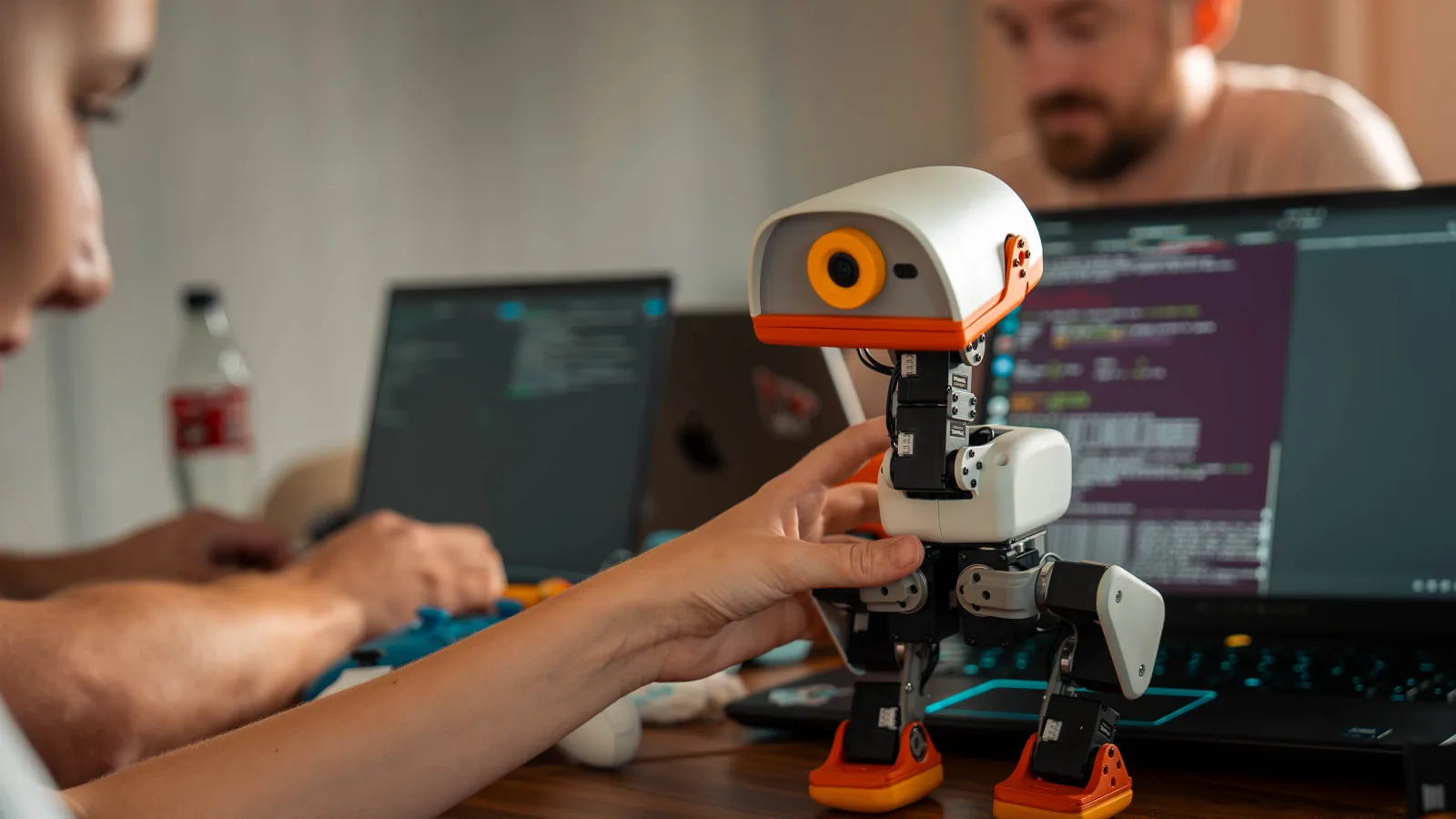 A child touching a small robot next to a laptop