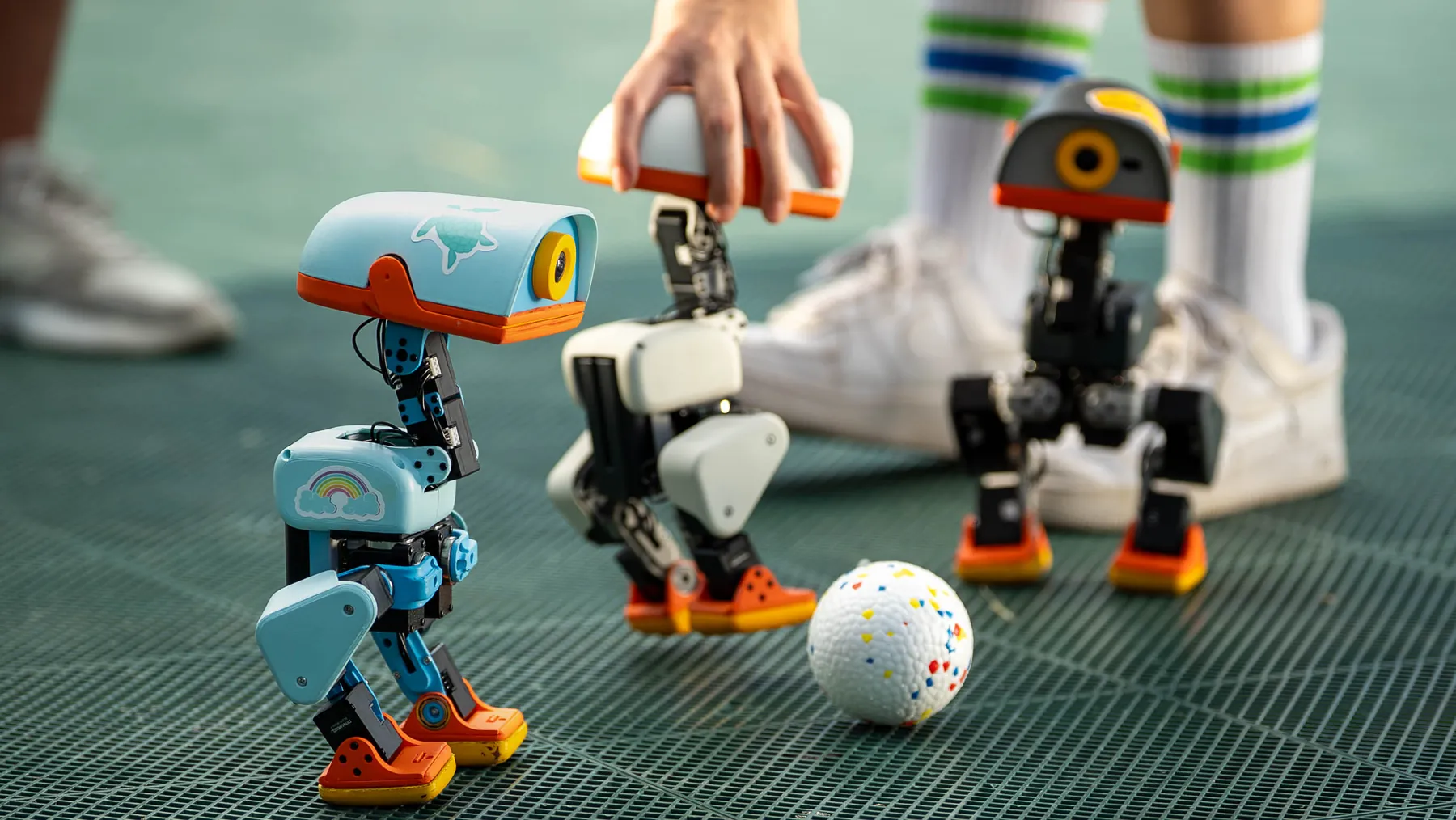 Kids playing football with small walking robots